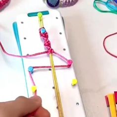 someone is doing something with colored yarn and crochet hooks on a white table