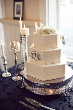 a three tiered cake sitting on top of a table next to silverware and candles