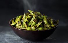 a bowl filled with green beans sitting on top of a table