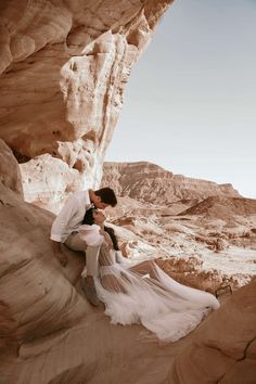 a man and woman sitting on rocks in the desert