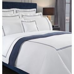 a bed with white sheets and blue trimmings