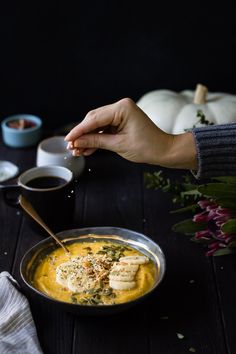 a person is sprinkling some kind of food into a bowl on a table