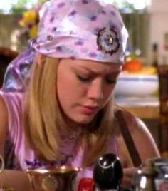 a woman in a pink shirt is looking at some cups on a table and has her eyes closed