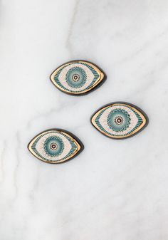 three decorative ceramic plates on a white marble countertop with blue and green circles in the center