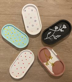 four oval trays with designs on them sitting on a wooden table next to each other