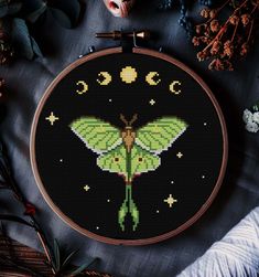 a cross stitch pattern with a green moth on it's back and stars in the background