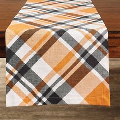 an orange and black plaid table runner on a wooden table