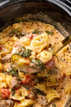 a ladle full of pasta and meat in a crock pot