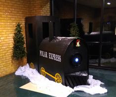 a fake replica of a train on display in front of a brick building with snow around it