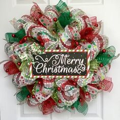 a christmas wreath on the front door decorated with ribbons and bowes that says merry christmas