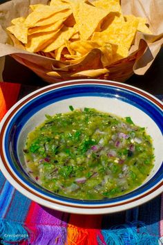 a bowl of guacamole with tortilla chips next to it on a table