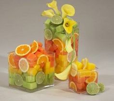 two clear vases filled with fruit and flowers