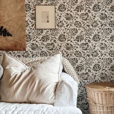 a white couch sitting next to a wall covered in black and white damask paper