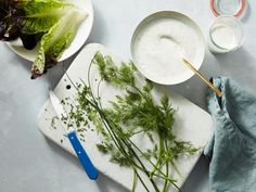 some vegetables are sitting on a cutting board next to bowls and utensils with dips in them