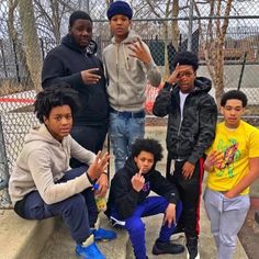 the young men are posing together for a photo in front of a chain link fence