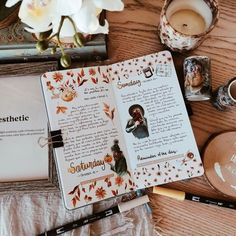 an open book sitting on top of a wooden table next to some candles and other items