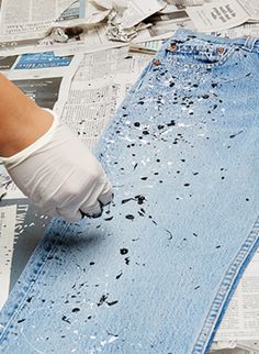 a person in white gloves is working on an old pair of jeans with torn edges