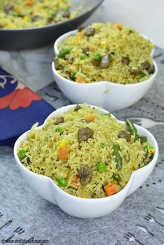 two bowls filled with rice and vegetables on top of a table next to a blue napkin