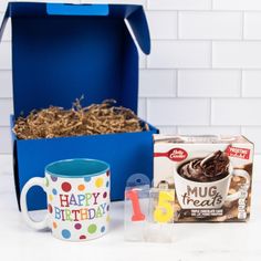 a blue box with coffee, mugs and other items sitting on a white table