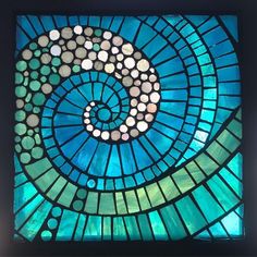 a blue and green stained glass window with a spiral design