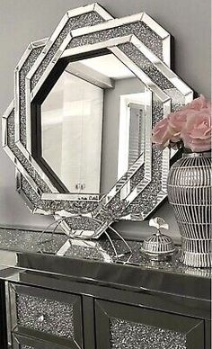 a mirror sitting on top of a dresser next to a vase with flowers in it