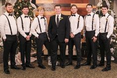 a group of men standing next to each other in front of a christmas tree