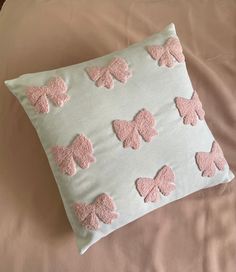 a pillow with pink butterflies on it sitting on top of a white bed sheet,