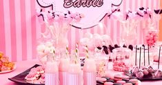 a table topped with lots of desserts next to a pink wall and sign that says hello kitty