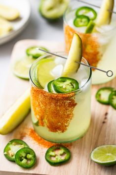 two glasses filled with cucumber, lime and pepper sprinkles on a cutting board