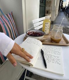 a person is sitting at a table with an open book and some food on it