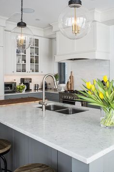 a kitchen with an island, sink and two hanging lights