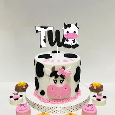 a cow cake with cupcakes on the side and a sign that says tut