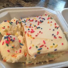 a plastic container filled with white frosting and sprinkles