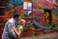 a man and woman standing in front of a colorful building