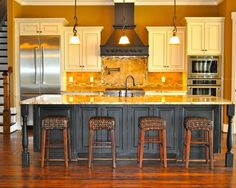 a large kitchen with an island in the middle and three stools next to it