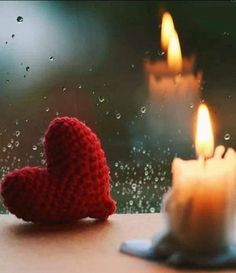 two knitted hearts sitting next to each other on a window sill with water droplets