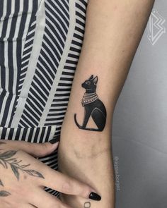 a woman's arm with a small black cat tattoo on the left side of her wrist