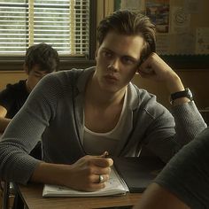 two people sitting at a table with notebooks in front of them and one person writing