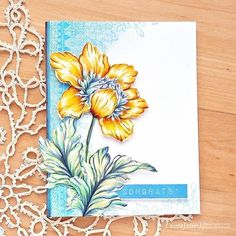 a close up of a greeting card on a table with doily and flowers in the background