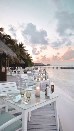 tables and chairs are set up on the dock by the water at sunset or dawn