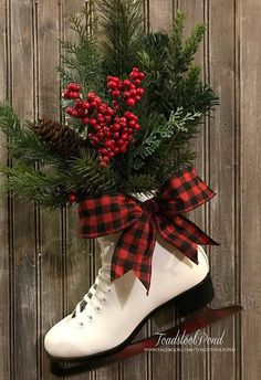 a pair of ice skates decorated with berries and pine cones is hanging on a wooden wall