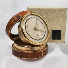 an old fashioned clock sitting on top of a wooden stand next to a box with it's lid open