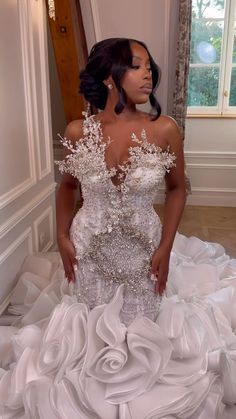 a woman in a white wedding dress standing next to a window