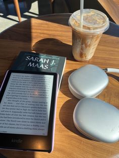 a tablet sitting on top of a wooden table next to a cup of coffee and a book