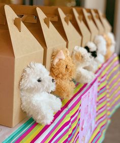 stuffed animals are lined up in front of brown paper bags on a table with colorful stripes