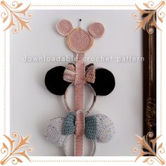 a crocheted mickey mouse head hanging on a wall next to a frame with an ornate border around it