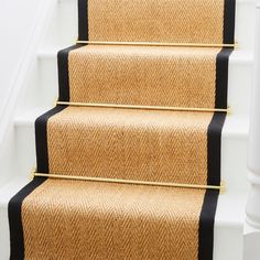 a carpeted stair runner with black trim on the bottom, and yellow handrails