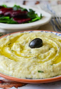 hummus with olives in a bowl on a table