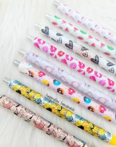 five pens are lined up next to each other on a white surface with different designs