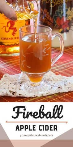 a glass pitcher filled with apple cider sitting on top of a table